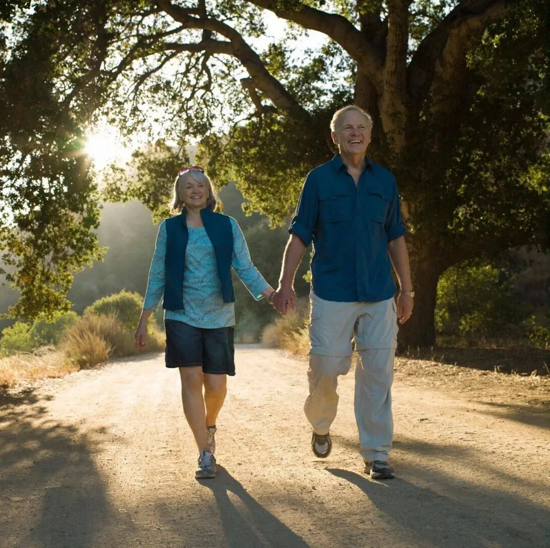 A man and woman holding hands while walking down the road.